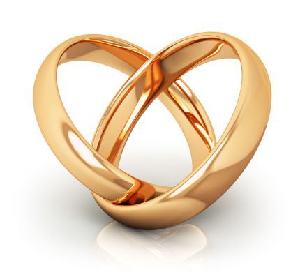 Creative abstract love, engagement, proposal and matrimony concept: macro view of pair of shiny golden wedding rings connected into heart shape isolated on white background with reflection effect